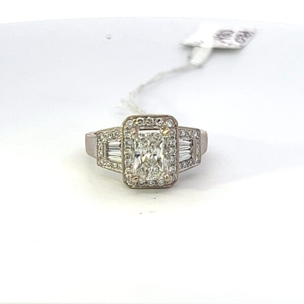 This has a 2.03 carat Radiant Cut natural mined diamond that is an J in color and SI2 clarity with a Gemological Institute of America Diamond Grading Report. Set in a 18 kt Halo ring with side tapered baguette and full cut round natural diamonds with an additional total weight of 1.16 carats total weight. Total of all diamonds equals a 3.19 carats.